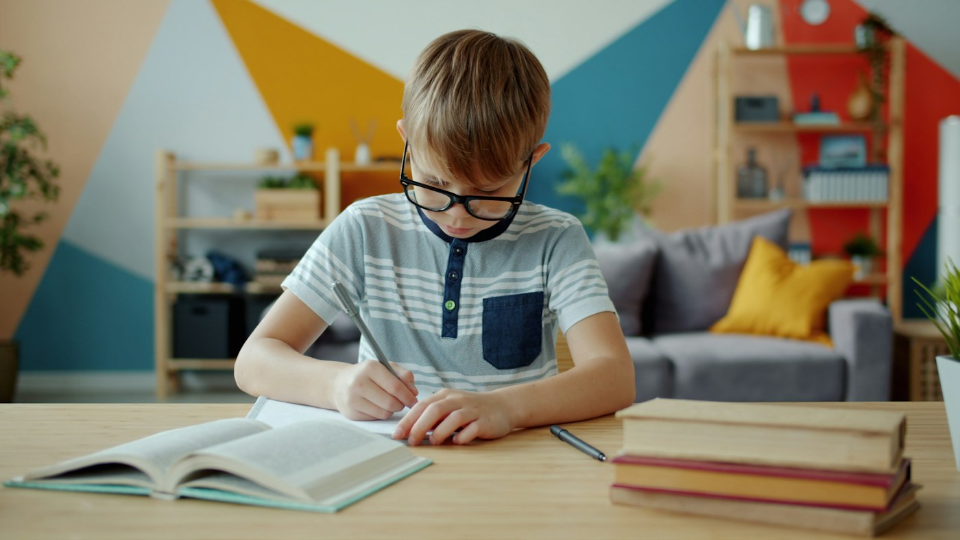 A young boy writing in his workbook at a desk
